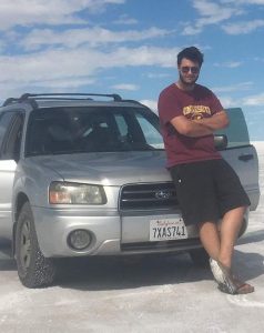 Man leaning against Silver Subaru Forester in a salt flat