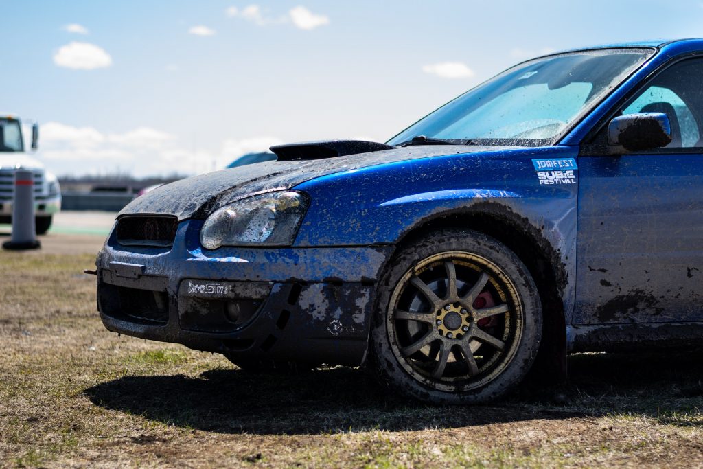 Blue Subaru STI covered in brown mud