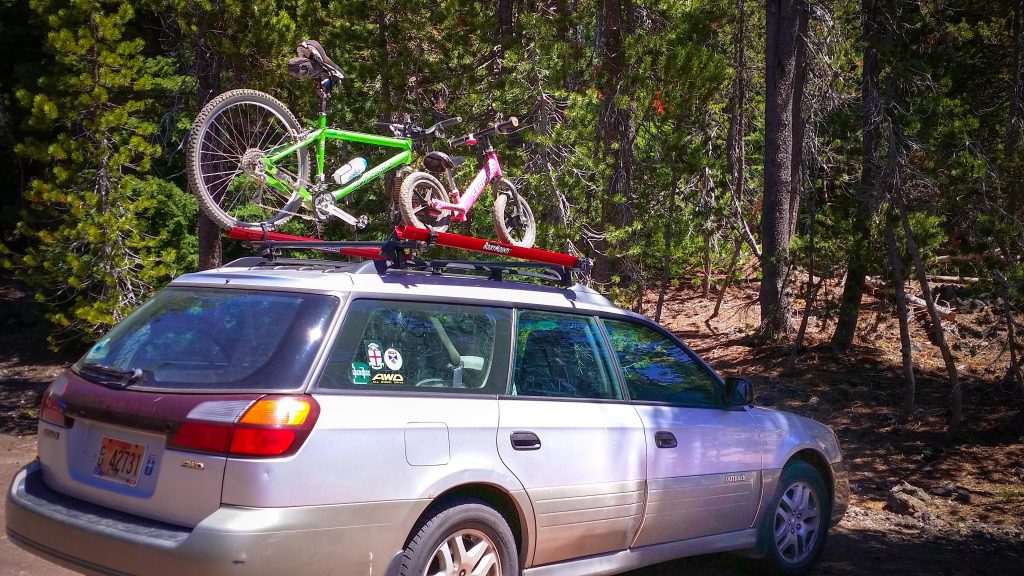Bikes mounted on the roof of a white Subaru outback