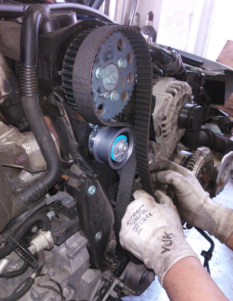 Mechanic fitting a new timing belt onto an engine